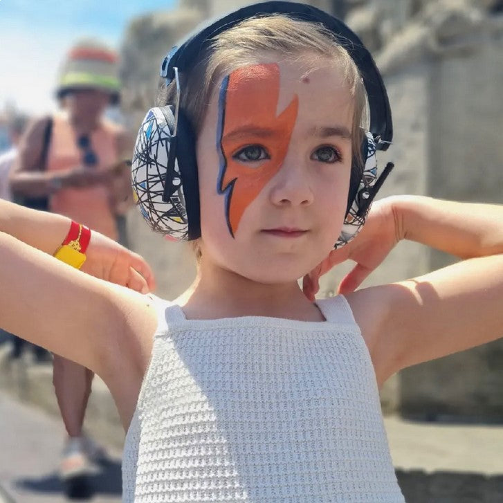 A child wearing Banz Kids Earmuffs in the Squiggle pattern