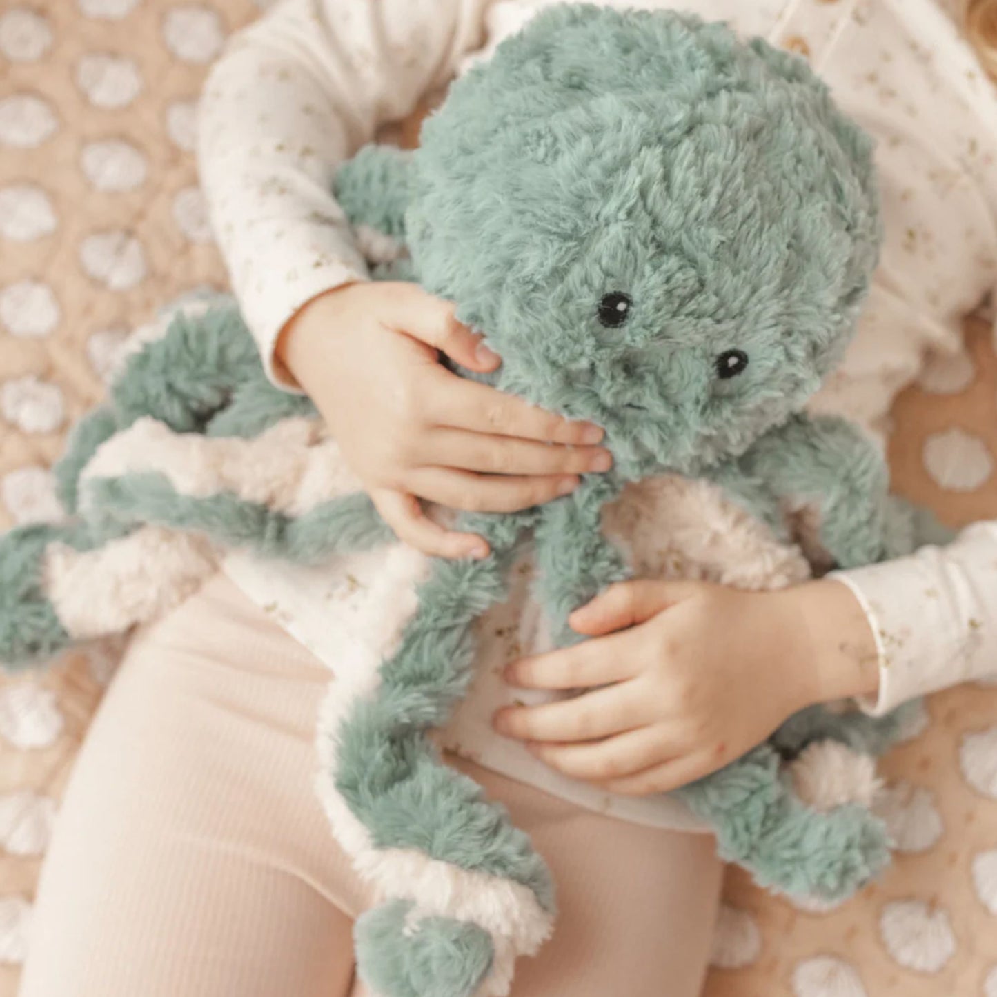 Child lying down with Ollie the Weighted Octopus weighted stuffed plush